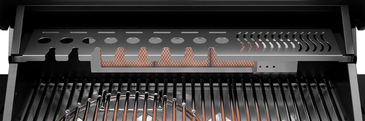 Wnętrze grilla gazowego z widocznymi metalowymi rusztami i elementami grzewczymi. Na górze znajduje się perforowana metalowa osłona z otworami i wycięciami.