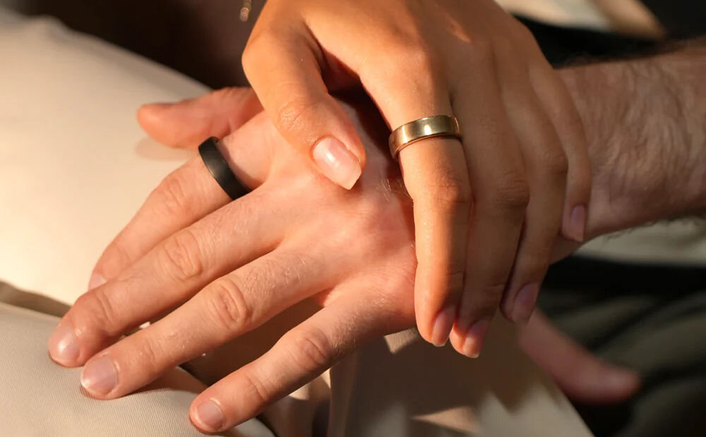 Smartring RINGCONN Gen 2 dwie dłonie jedna na drugiej z założonymi pierścieniami grubość 2mm szerokość 6,8 mm waga do 3 gram nagroda iF Design Award