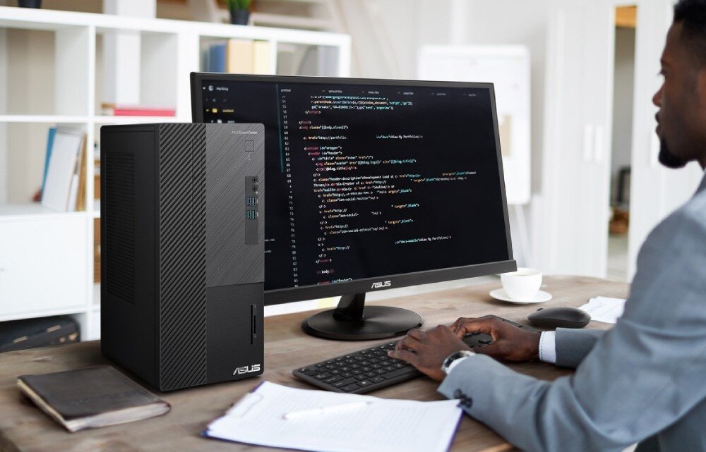 Komputer ASUS ExpertCenter D500ME-513500342X Osoba w garniturze pracująca przy biurku z komputerem stacjonarnym i monitorem, na ekranie widoczny jest edytor kodu, wielkość, obudowa, przeznaczenie, wygląd