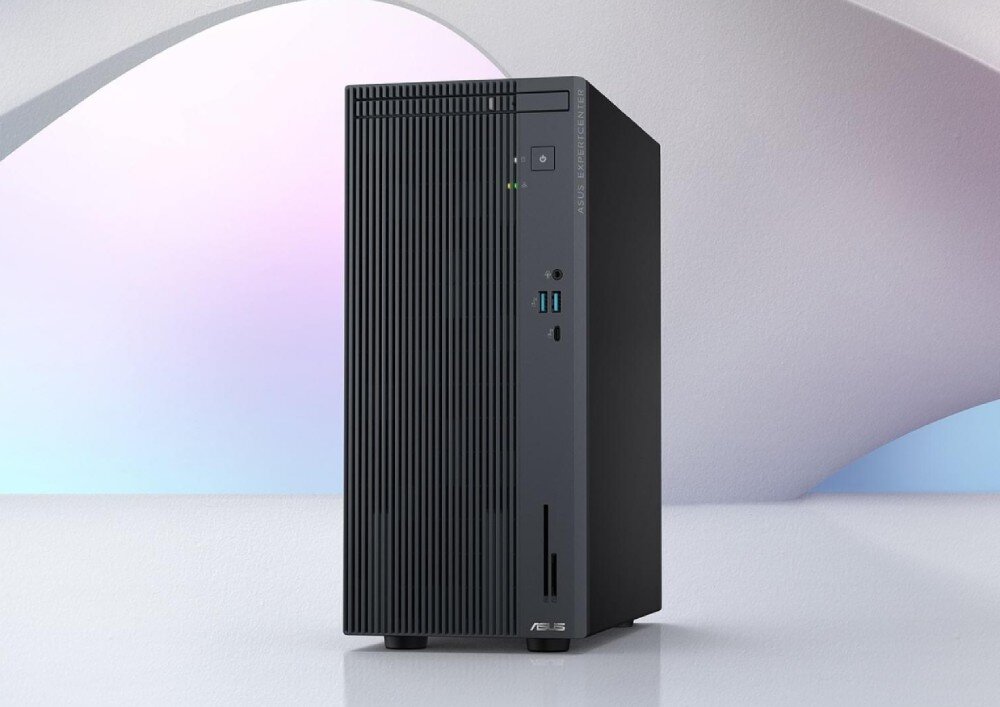 Komputer ASUS ExpertCenter P500MV-13420H057X Czarna obudowa komputera stojąca na białej powierzchni, z pionowymi żebrowaniami na froncie i włącznikiem oraz portami USB w górnej części panelu przedniego, opis