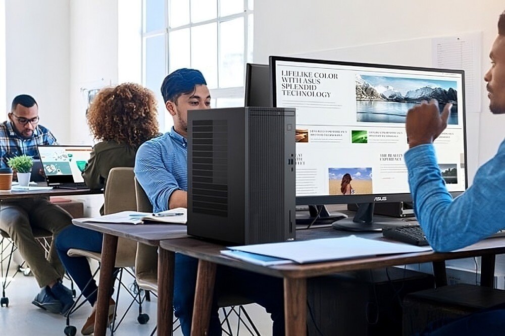 Komputer ASUS ExpertCenter P500MV-13420H057X Biuro z kilkoma osobami pracującymi przy biurkach, na pierwszym planie komputer stacjonarny obok dużego monitora wyświetlającego stronę internetową, przeznaczenie, obudowa, cechy