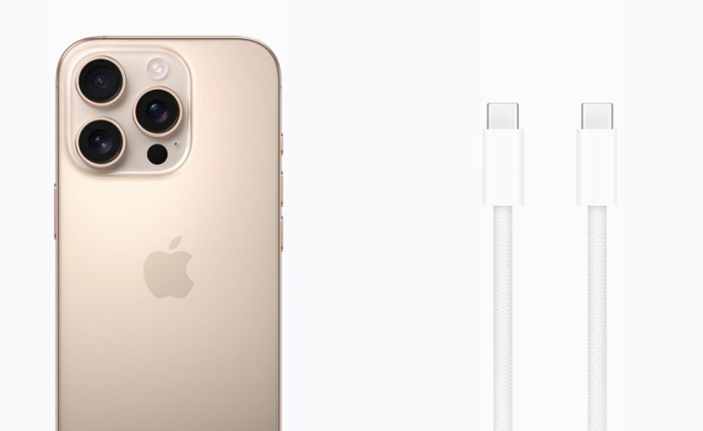 Na obrazie widoczny jest tył smartfona w kolorze złotym z trzema dużymi obiektywami aparatu oraz logo w kształcie nadgryzionego jabłka. Obok znajduje się biały kabel z końcówkami USB-C.