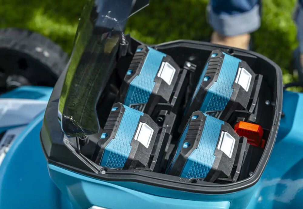 Kosiarka akumulatorowa DEDRA SAS+ALL DED6997X-2A5 ogród trawnik zbliżenie na otwór na akumulatory w otworach cztery akumulatory kompatybilna z akumulatorami z uniwersalnej serii DEDRA SAS+ALL wymaga dwóch akumulatorów do pracy w zestawie dwa akumulatory o pojemności 5,0 Ah czas pracy około 35 minut ładowarka czas ładowania około 140 minut