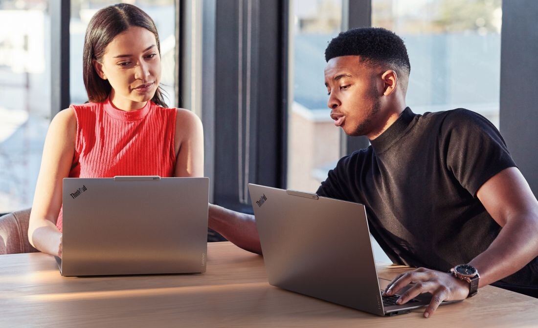 Dwoje współpracowników pracujących na laptopach Lenovo ThinkPad przy stoliku w biurze - Shield Mode  