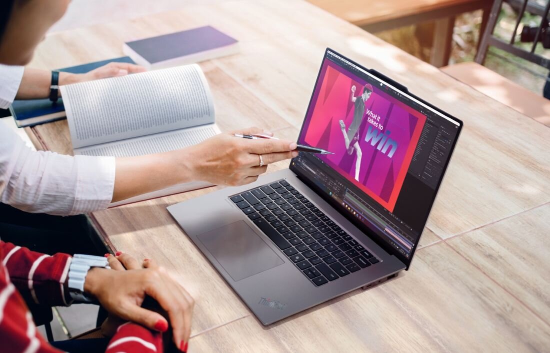 Osoba pisząca dokument tekstowy na laptopie Lenovo ThinkPad przy drewnianym stole w miejscu pracy - Wellness Mode 