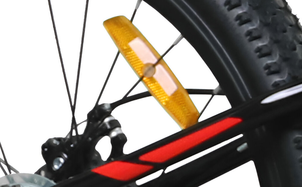 Zbliżenie na tylne koło roweru z czarno-czerwoną ramą i pomarańczowym odblaskiem na szprychach. Widoczny jest również fragment hamulca tarczowego.