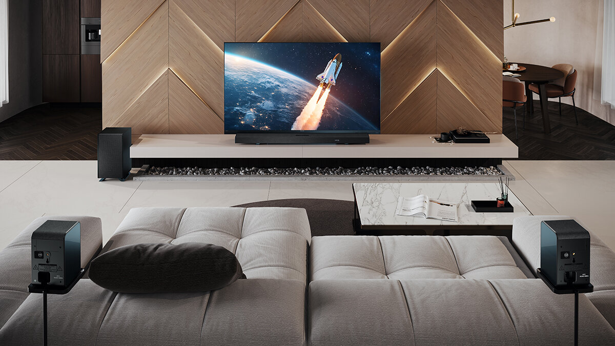 Kolumny głośnikowe SHARP HT-SPR52021 kinowe wrażenia Dolby Atmos DTS:X, głośniki stojące na podstawkachza kanapą skierowane w strone telewizora