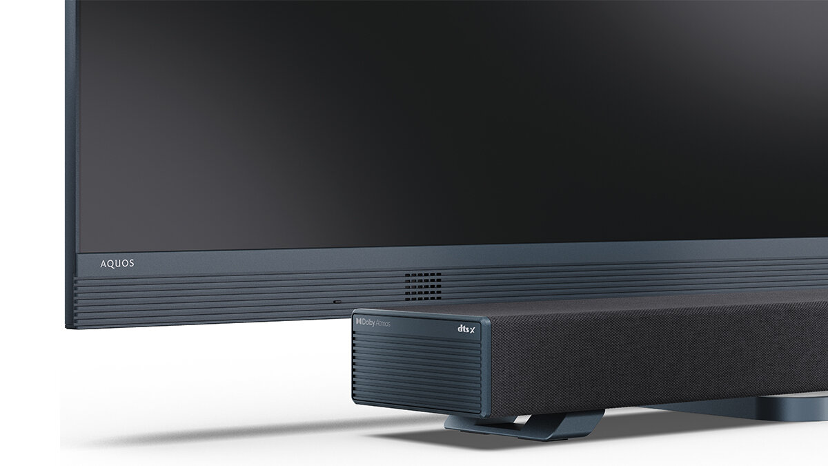 Soundbar SHARP HT-SBW53121 design czarna tkanina elegancja, kadr soundbara z nóżkami stojącego obok telewizora