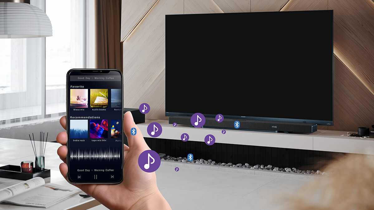 Soundbar SHARP HT-SBW53121 Bluetooth 5.3 bezprzewodowe odtwarzanie, soundbar stojący na szafce pod telewizorem, osoba trzymająca smartfon w ręku