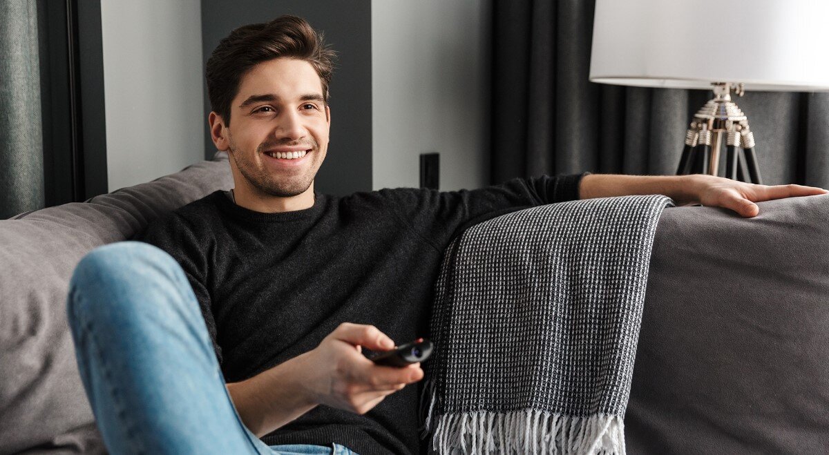 Soundbar SHARP HT-SBW53121 HDMI eARC korektor regulacja basu i tonów, osoba siedząca na kanapie z pilotem w ręku