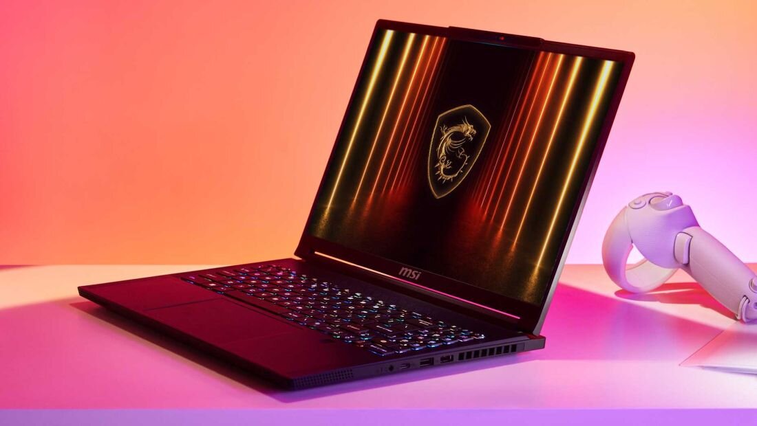 Laptop MSI Stealth A16 AI+ z podświetlaną klawiaturą, wyświetlaczem prezentującym logo MSI na tle pomarańczowych i żółtych linii świetlnych, obok kontroler do gier, kolorowe oświetlenie w tle. - LPDDR5x-7500 NVMe SSD PCIe Gen4