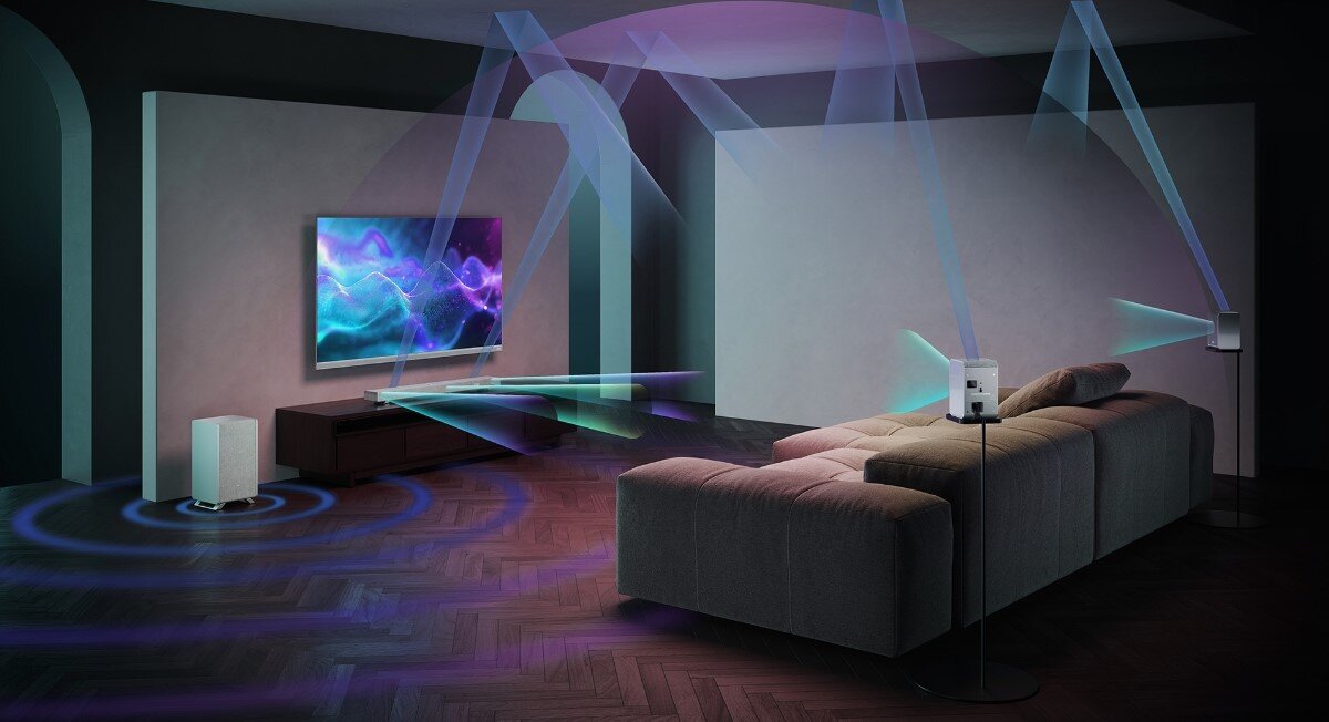 Kolumny głośnikowe SHARP HT-SPR52021 tylne głośniki otaczające naturalny dźwięk, telewizor zawieszony na ścianie, głosniki rozstawione po całym pomieszczeniu wydające dźwięk