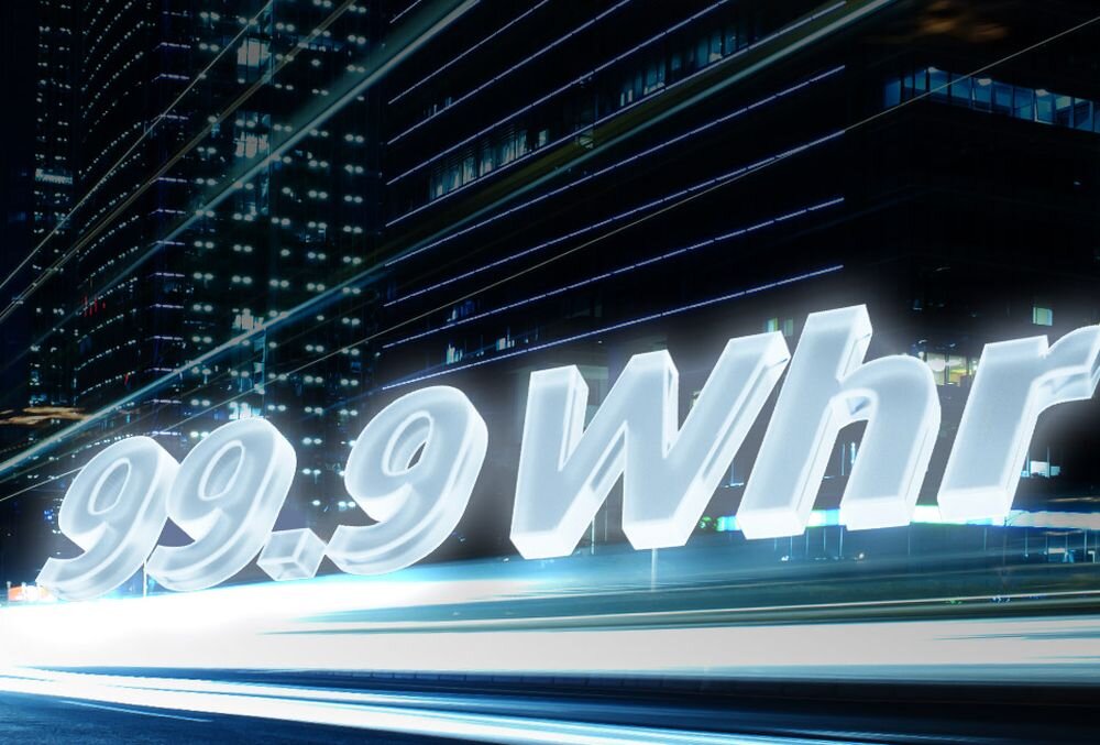 Graficzna wizualizacja dużej pojemności baterii – trójwymiarowy, podświetlony napis „99.9 Whr” na tle dynamicznych smug światła w nocnym mieście, co symbolizuje długi czas pracy i mobilność. - Bateria 99.9 Whr