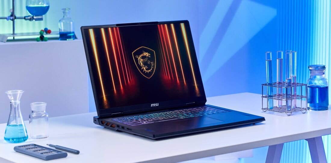 Otwarty laptop MSI Vector na białym stole laboratoryjnym, otoczony przez probówki i zlewki z kolorowymi płynami; na ekranie wyświetlone jest podświetlone na pomarańczowo logo gamingowe MSI Dragon, co podkreśla moc i precyzję urządzenia. - Stworzony dla profesjonalistów, opis serii Vector