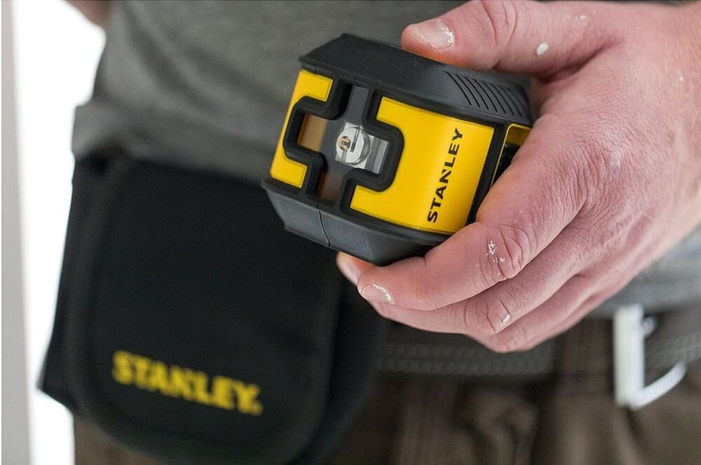 Laser krzyżowy STANLEY STHT77649-1, zielona, linia, zasięg, samopoziomowanie, poziomica laserowa Stanley Cubix trzymana w dłoni. 