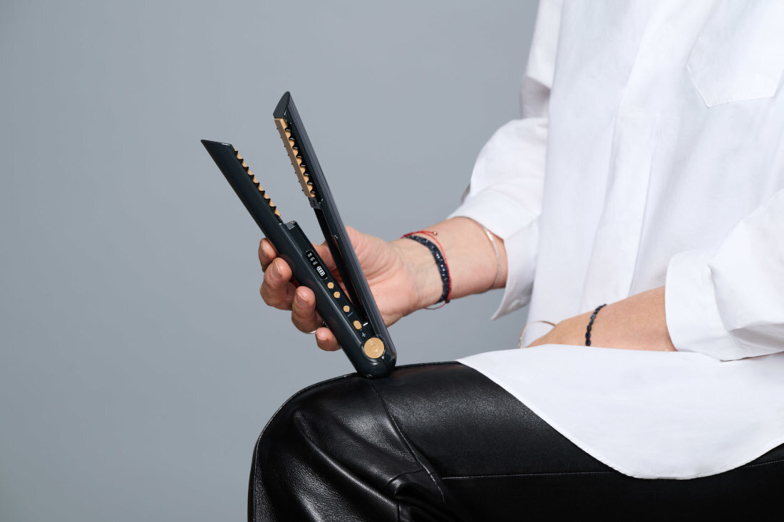 Prostownica SKINVIBE Luna Miniwireless SV-003BK Czarny 210 stopni osoba trzyma w rękach dwie prostownicę białą i czarną przyciski płytki grzebień jasne tło wszechstronne narzędzie profesjonalna stylizacja włosów zaokrąglona obudowa precyzyjne rozprowadzanie ciepła unikalny styl gładkie lśniące pasma lekkie niedbałe fale sprężyste loki pełne objętości