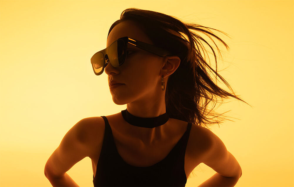 Okulary XREAL One Czarny prezentacja okularów założonych na kobiecie na żółtym tle kompatybilność integracja z ulubionymi urządzeniami Mac PC iOS Android