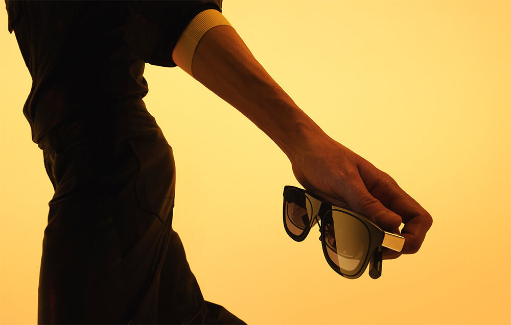 Okulary XREAL One Czarny prezentacja okularów trzymanych w dłoni na żółtym tle bezprzewodowe panel z matrycą przycisków 2D/3D reakcja na proste gesty dłonią wygodna obsługa