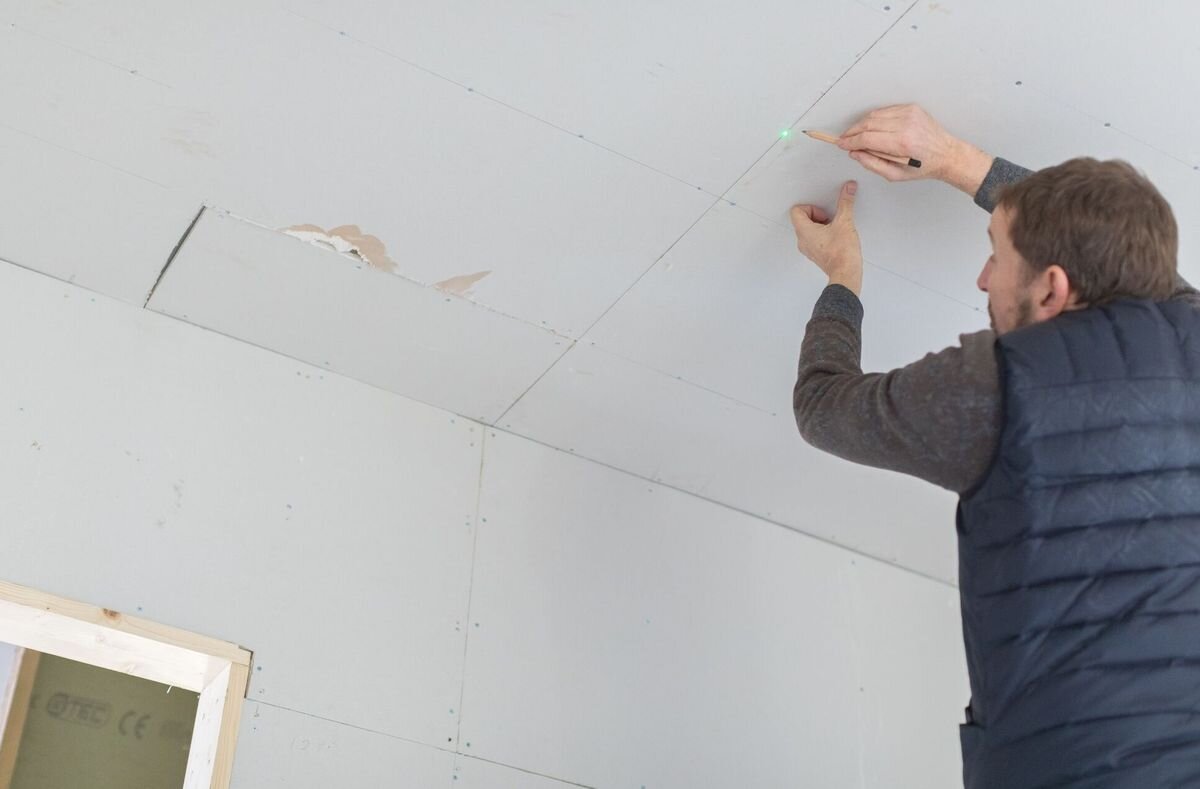 Laser krzyżowy STANLEY Fatmax FMHT77596-1, moc, zieleń, laser, remont, mężczyzna odmierza linie laserem na suficie