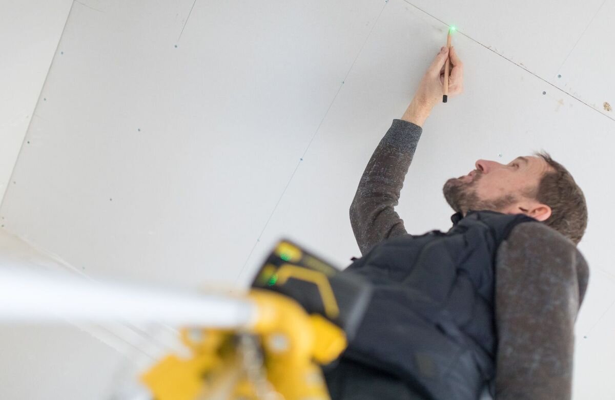 Laser krzyżowy STANLEY Fatmax FMHT77596-1, metr, wynik, pomiar, zasięg, mężczyzna kreśli linie na suficie
