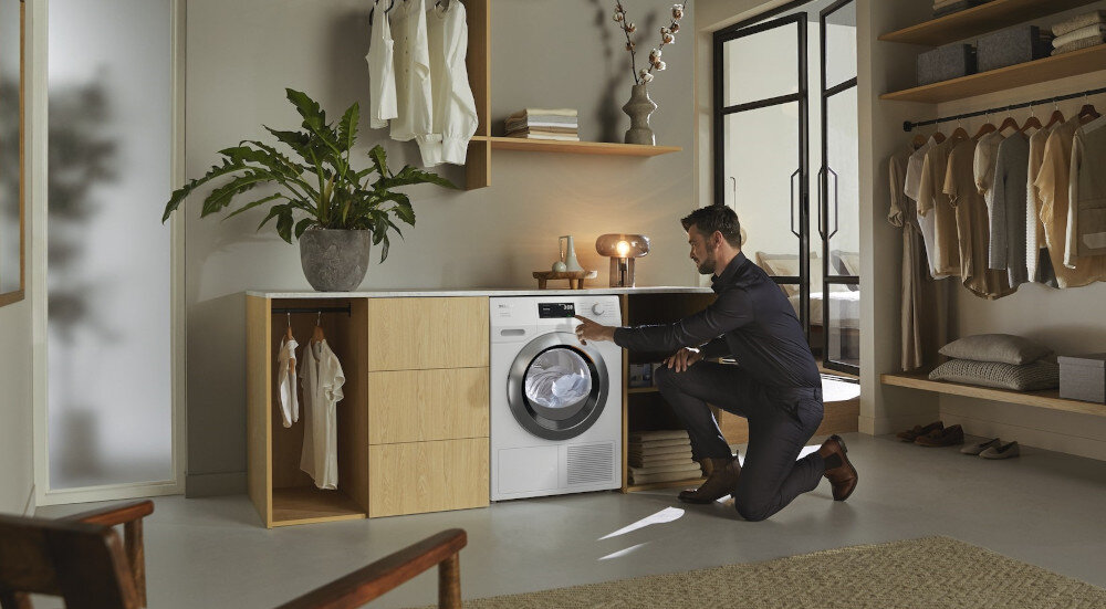 Suszarka MIELE TEH 795 WP EcoSpeed zdjęcie wizualizacyjne lifestyle pomieszczenie mężczyzna zmiana ustawień panel Optymalna ochrona domu optymalne wartości szczelności ochrona domu mebli pomieszczeń
