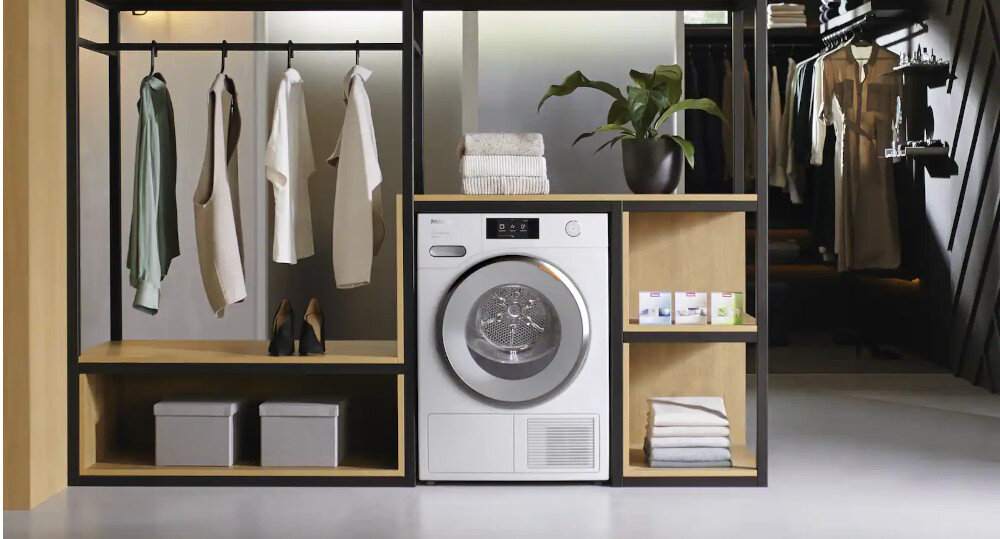 SUSZARKA MIELE TED645 WP wizualizacja garderoba ubrania na wieszakach suszarka w obudowie półki pudełka dekoracje ręczniki roślinka obuwie na półce szczelność klasa kondensacji A Optymalna ochrona domu mebli bez tworzenia się kondensatu