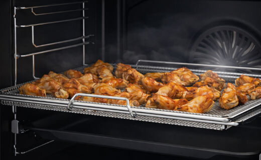 Funkcja AirFry w piekarniku Beko – chrupiące skrzydełka z kurczaka pieczone bez tłuszczu na specjalnej metalowej tacy z siatki.