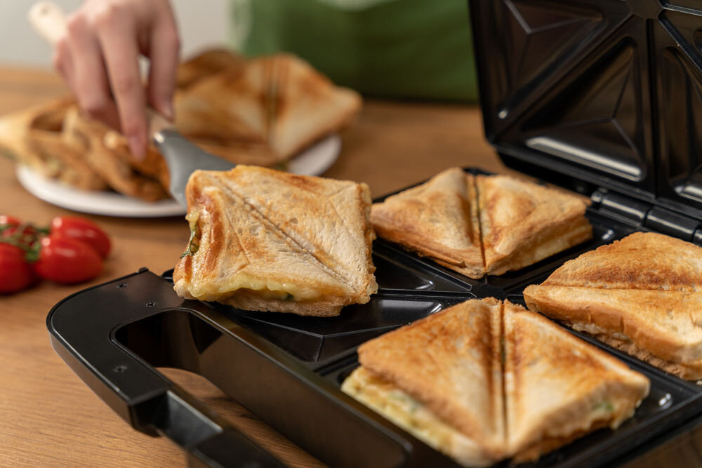 Opiekacz GOTZE & JENSEN SM703X zbliżenie na wnętrze opiekacza osoba wyjmująca jedną z kanapek