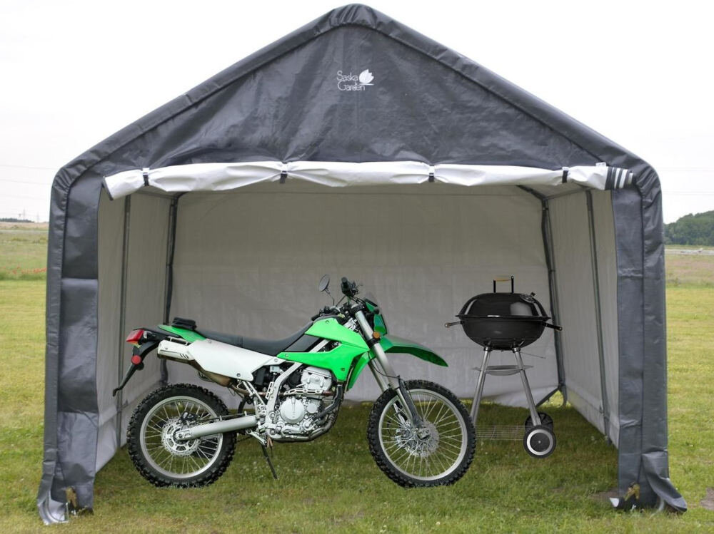 Szary pawilon ogrodowy z logo \'Saska Garden\' na górze, wewnątrz którego znajduje się zielony motocykl i czarny grill na kółkach. Pawilon stoi na trawie, a w tle widać otwartą przestrzeń.