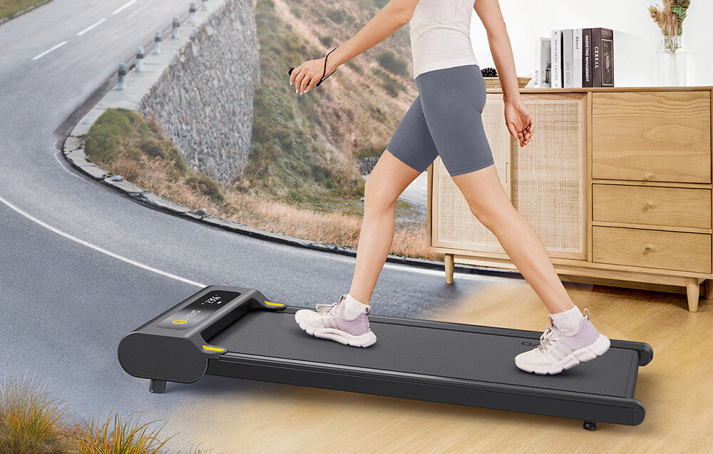 Bieżnia elektryczna UREVO E3S 1654.87W 6.4 km-h Kobieta maszerująca na bieżni biurkowej UREVO w salonie; graficzne przejście między wnętrzem domu a asfaltową drogą.