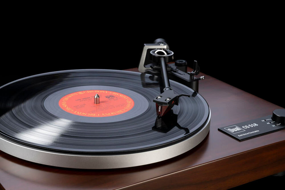 Gramofon DUAL CS 518 napęd paskowy, serwosilnik prądu stałego, amortyzacja drgań, synchronizacja prędkości 33-45-78 RPM, gramofon po skosie na czarnym tle