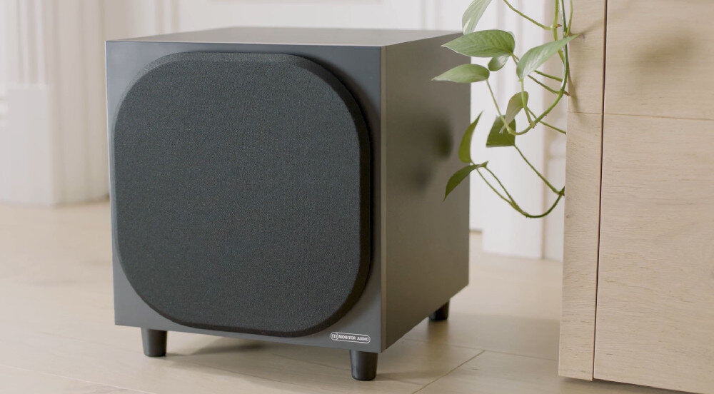 Subwoofer MONITOR AUDIO Bronze W10 6G - Większa efektywność dźwięku, Subwoofer stojący na podłodze obok szafki
