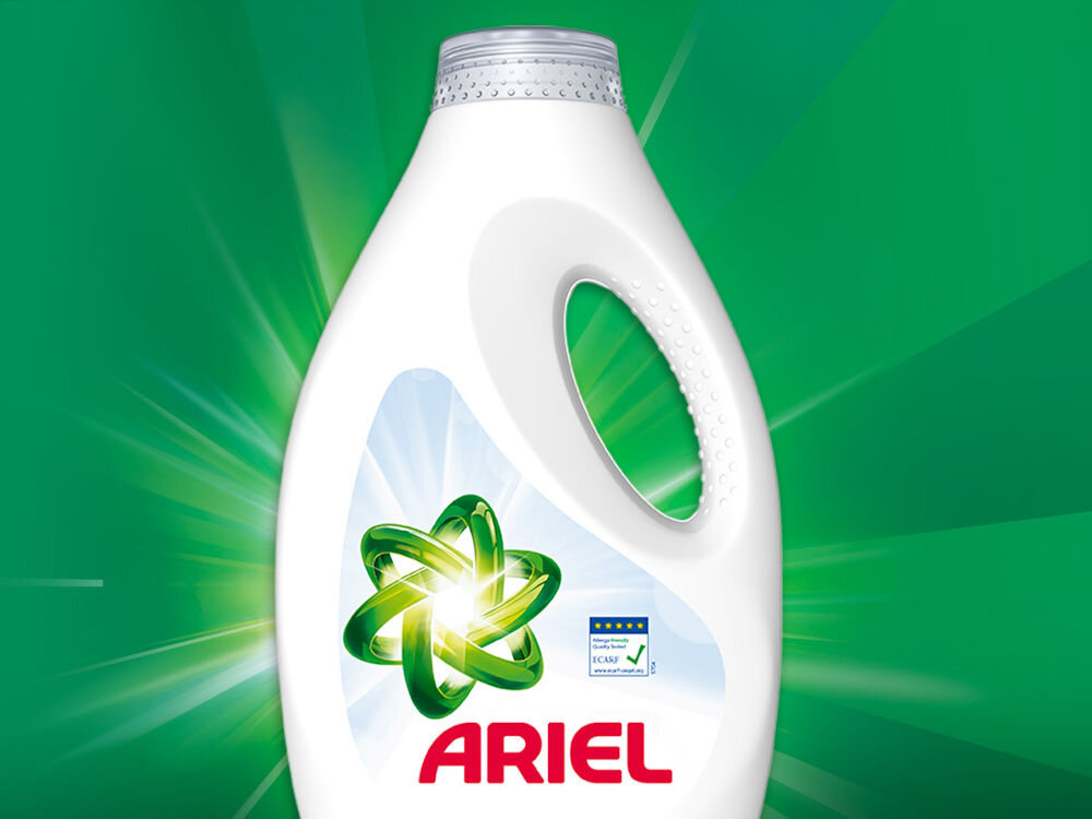 Płyn do prania ARIEL Sensitive 2250 ml do kolorowych tkanin Biała butelka płynu do prania ARIEL Sensitive z zielonym symbolem atomu na tle rozchodzących się promieni świetlnych