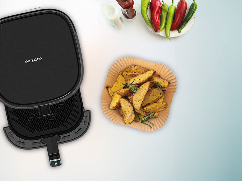 Foremki papierowe CECOTEC Cecofry Paper Pack do Air Fryer 20-24 cm (150 sztuk) uniwersalne akcesorium czarna frytkownica otwarty kosz obok papierowa foremka z ziemniakami w środku