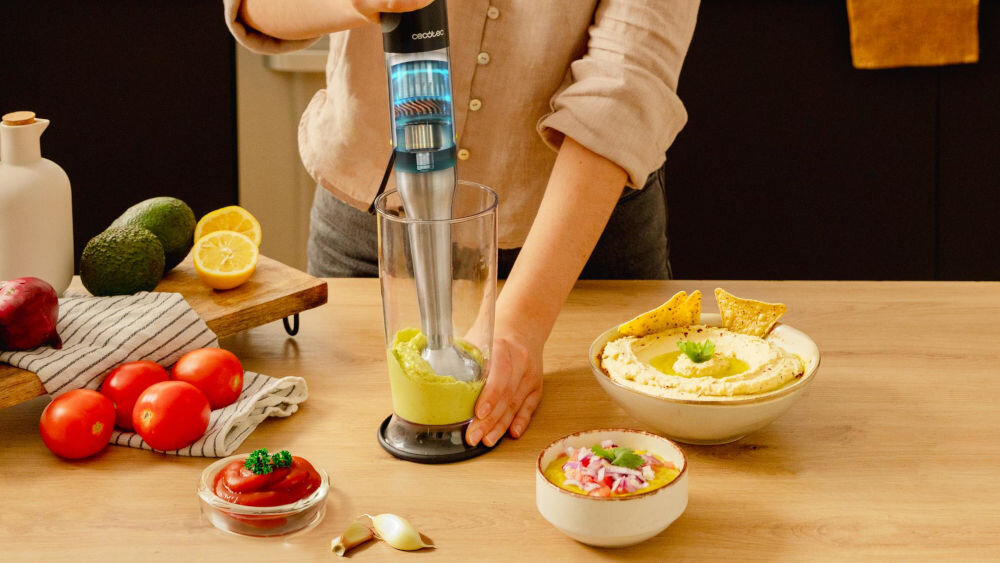 Blender CECOTEC Katana 15 Smash Bosoba trzyma w ręku blender blenduje zieloną zawartość w przeźroczystym pojemniku moc 1500 W nawet z twardymi składnikami kremowa zupa smoothie z mrożonych owoców domowy pasztet działa szybko i bez wysiłku efektywność wygoda pracy błyskawiczne działanie precyzja przetwarzania składników 