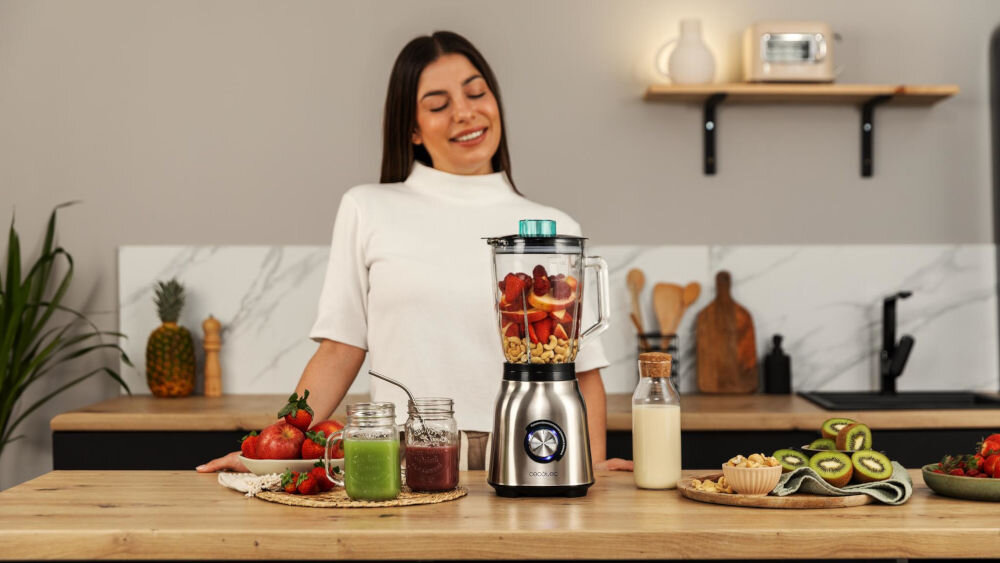 Blender kielichowy CECOTEC Power Black Titanium 1800 MAX Blend It Efektywne miksowanie uśmiechnięta kobieta na blacie stoi srebrny blender pokrętło wewnątrz kielicha składniki