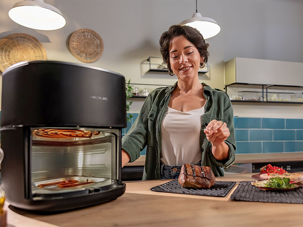Air Fryer Frytkownica beztłuszczowa CECOTEC CecoFry&Grill Duoheat 6500 3W1 z podwójną grzałką frytkownica wnętrze dwie grzałki u góry i na dole osoba trzyma na podstawce grillowane mięso podwójna grzałka szybkie równomierne gotowanie dwie niezależne grzałki precyzyjne rozprowadzenie ciepła grillowanie mięsa smażenie frytek pieczenie pizzy optymalny efekt wygoda szybkość zadowalające rezultaty
