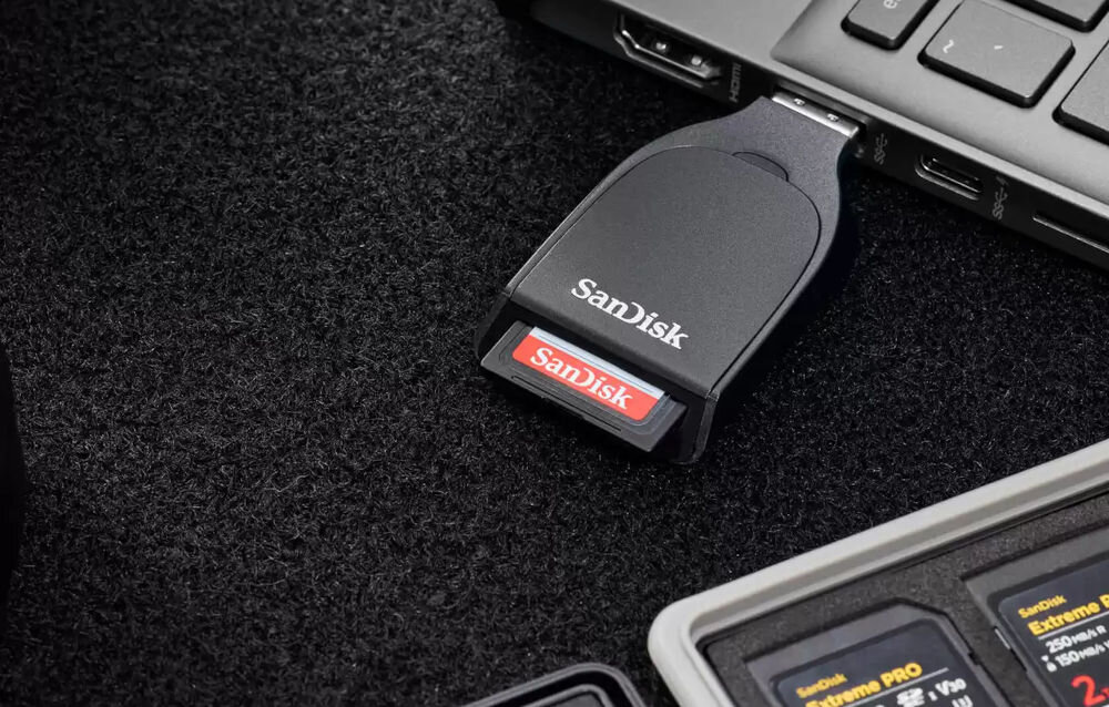 Czytnik kart SANDISK QuickFlow USB-A Czarny prezentacja czytnika wpiętego do laptopa z kartą w tle inne karty w etui szybki czytnik kart do zdjęć RAW i wideo 4K UHD