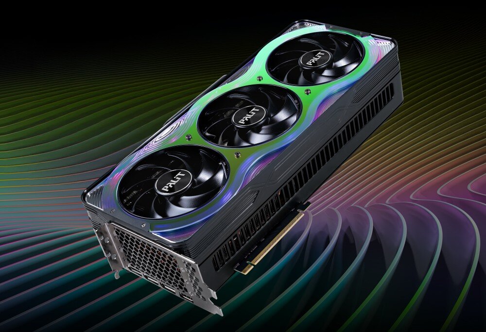 Karta graficzna PALIT GeForce RTX 5070 Ti GameRock 16GB Zdjęcie przedstawia kartę graficzną z trzema dużymi wentylatorami, umieszczoną na tle wielobarwnych, falistych linii. Obudowa karty ma połyskujący panel z gradientem przechodzącym od zieleni do fioletu, opis