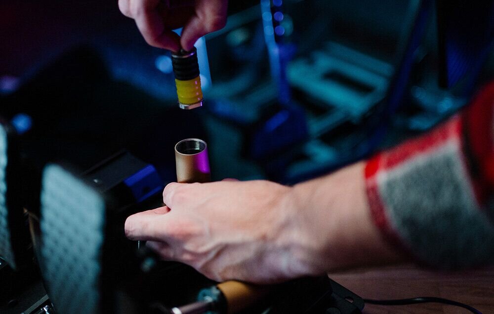 Zestaw MOZA Racing CRP2 RS066 prezentacja Zdjęcie prezentujące proces beznarzędziowej wymiany elastomerów w pedałach Moza CRP2 – dłoń użytkownika wyjmuje zestaw kolorowych gumek tłumiących z metalowej obudowy siłownika lotniczy stop aluminium obróbka CNC anodowanie stalowa podstawa karbonowa płyta pod pięty testy obejmujące ponad milion cykli pracy