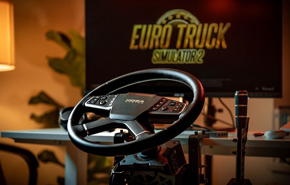 Kierownica MOZA Racing TSW RS060 (PC) Kierownica MOZA zamontowana na bazie przy biurku, w tle ekran startowy gry Euro Truck Simulator 2.