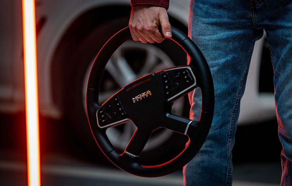 Kierownica MOZA Racing TSW RS060 (PC) Osoba trzymająca kierownicę MOZA Racing na tle koła samochodu z efektownym czerwonym podświetleniem krawędzi kierownica do ciężarówki, średnica 400 mm, realizm transportu