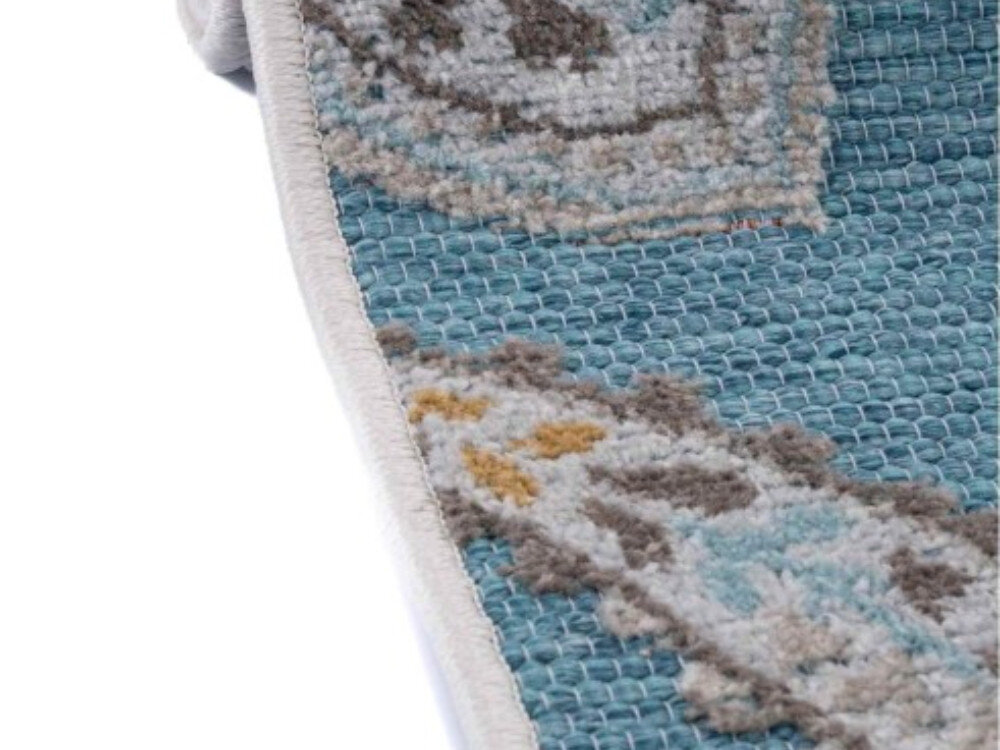 Dywan wewnętrzny MULTIDECOR Piar pnącze 160 x 230cm Turkusowy, polipropylen, trwałość, czyszczenie, kolor, na białym tle lekko rozwinięty dywan z jedną z krawędzi dywanu