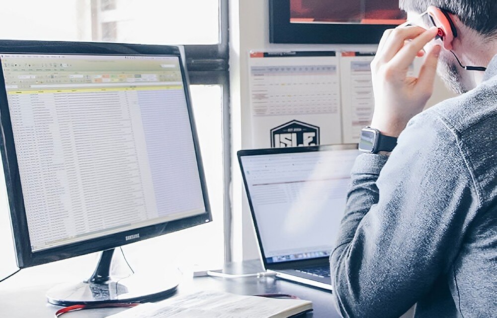 Router TP-LINK Archer MR402 Osoba siedząca przy biurku z laptopem i monitorem, skupiona na pracy przy arkuszu danych, zapora SPI, zabezpieczenia, VPN