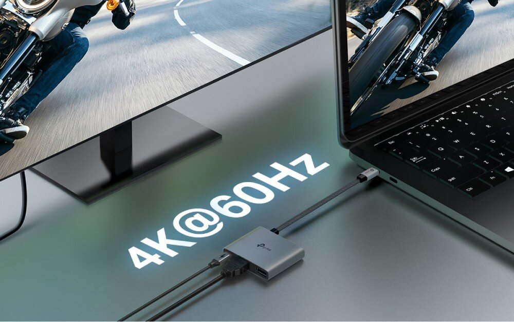 Hub TP-LINK UH3020C Adapter łączący laptopa z dużym monitorem, na którym wyświetlany jest ten sam obraz motocyklisty, z nałożonym napisem '4K@60Hz'