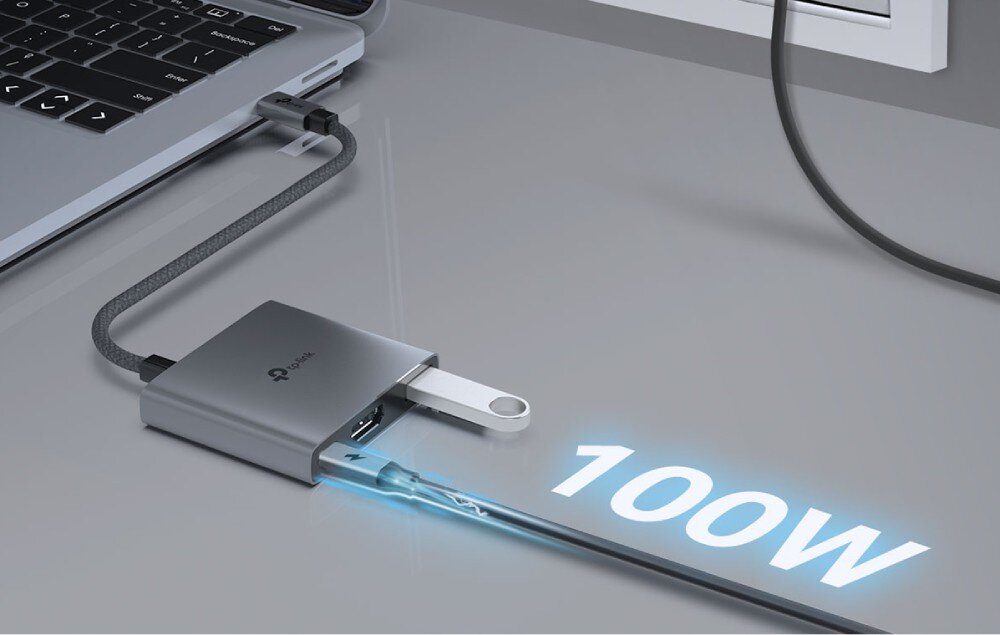 Hub TP-LINK UH3020C Zbliżenie na adapter podpięty do laptopa, do którego podłączony jest kabel zasilający z grafiką błyskawicy i napisem '100W' oraz srebrny pendrive