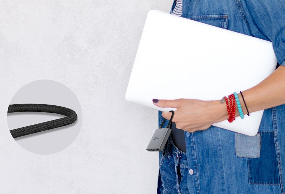 Hub TP-LINK UH3020C Osoba trzymająca biały laptop pod pachą, z przyczepionym do palca za pomocą kabla małym adapterem, obok zbliżenie na strukturę czarnego oplotu kabla