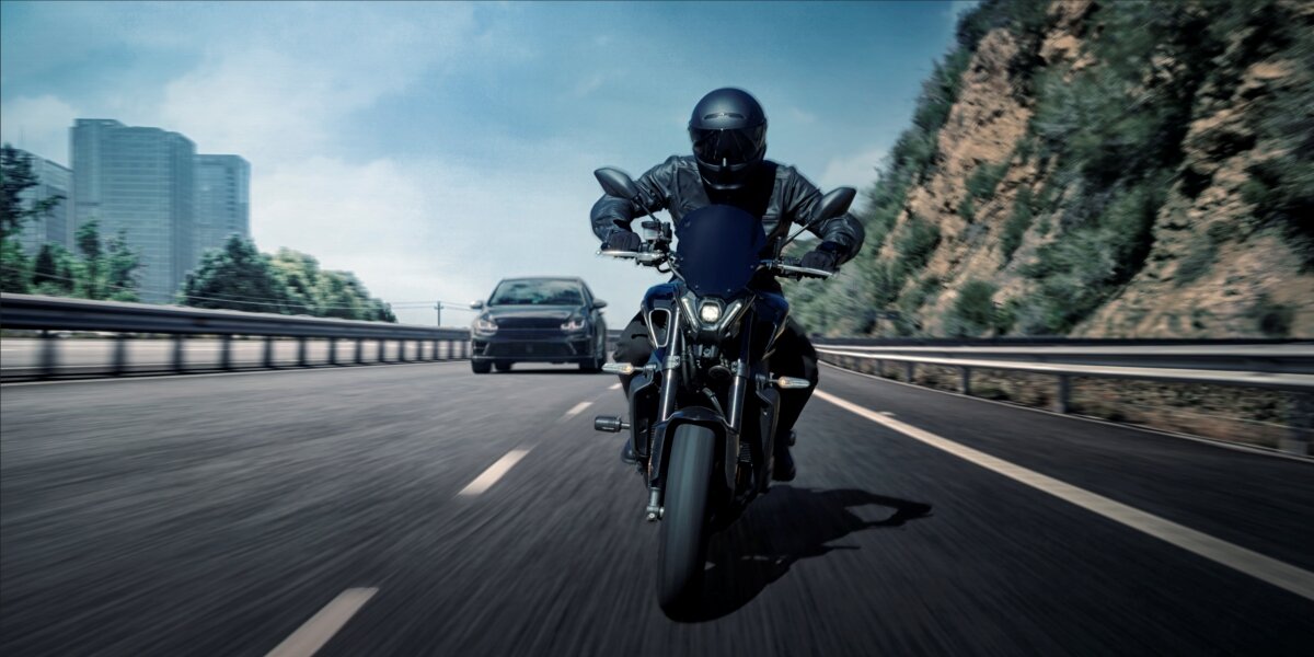 GARMIN Zumo R1 klasie odporności IP67 odporne na kurz i wodę deszczu zakurzonych szlakach - motocykl na drodze, za nim auto