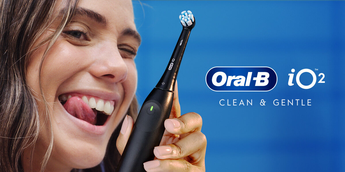 Osoba trzyma czarną szczoteczkę do zębów z widocznym logo Oral-B. Obok znajduje się napis \'Oral-B iO 2 CLEAN & GENTLE\'.