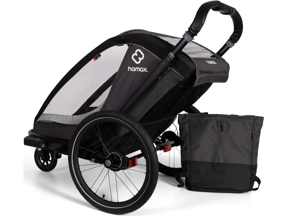 Przyczepka rowerowa HAMAX Cocoon One Szaro-czarnyprzyczepka na białym tle widoczna od tyłu pod skosem obok stoi torba Rączka z regulacją wysokości Powierzchnia z wegańskiej skóry Odpinana torba z tyłu